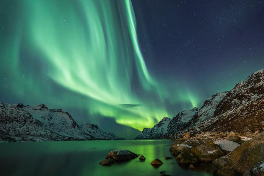 Aurora boreal sobre un lago entre montañas en Islandia. 