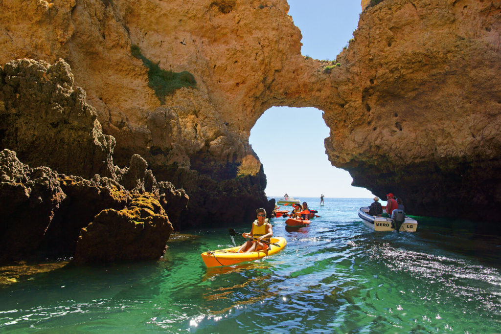 Kayakistas y un barco de tour en una de las muchas grutas, Ponta da Piedade, el Algarve, Portugal