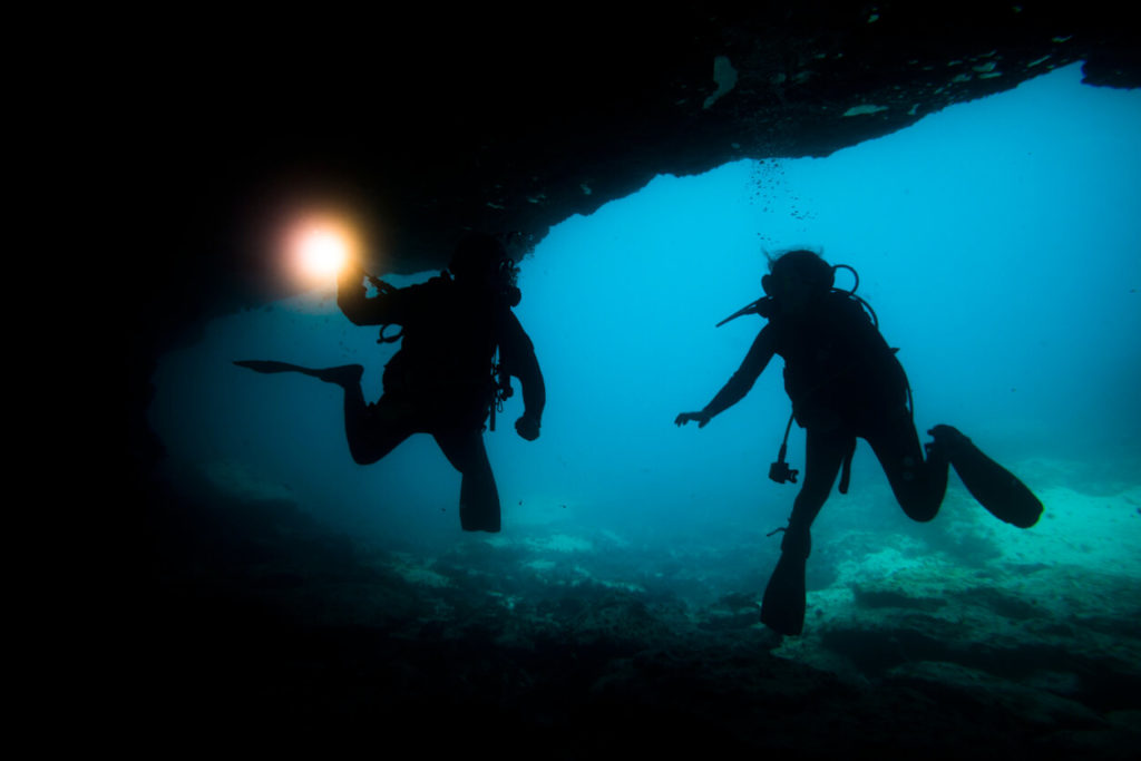 Buzos de la silueta en una cueva