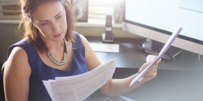 A businesswoman sits at her desk reading through paperwork