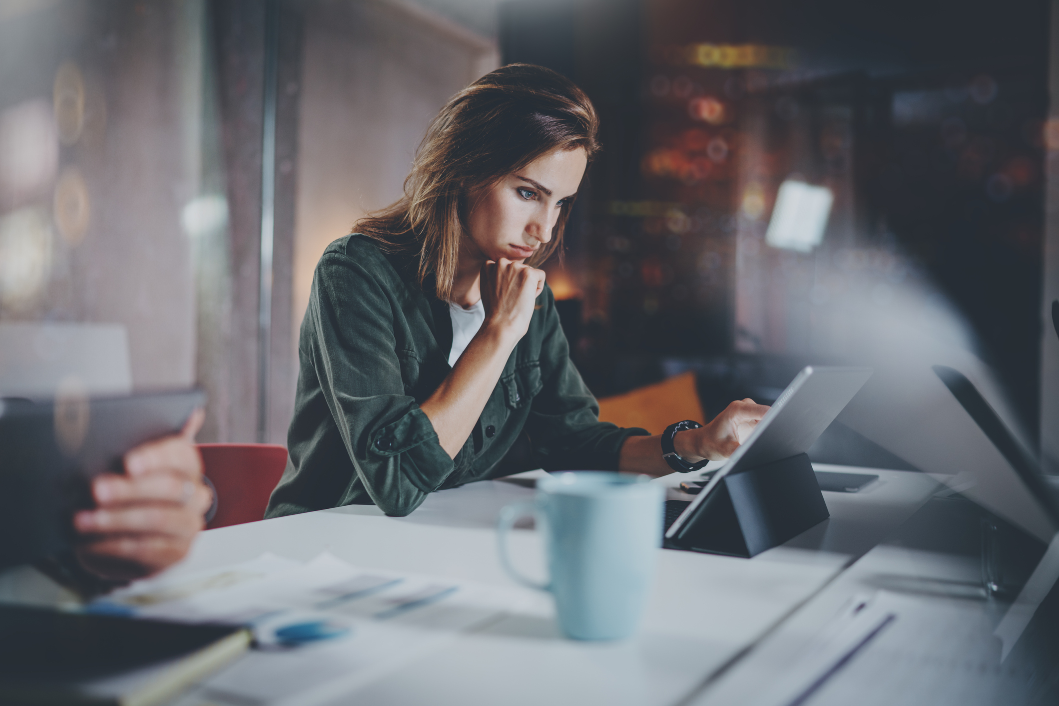 Compañeros de trabajo. Mujer joven que trabaja junto con colegas en el desván moderno de la oficina de la noche. Concepto del trabajo en equipo. Fondo borroso. Horizontal.